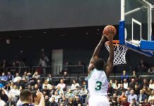 Basketball player dunks the ball in a crowded arena
