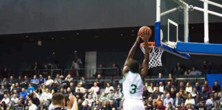 Basketball player dunks the ball in a crowded arena