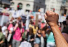 Raised fist in foreground at a crowded street protest