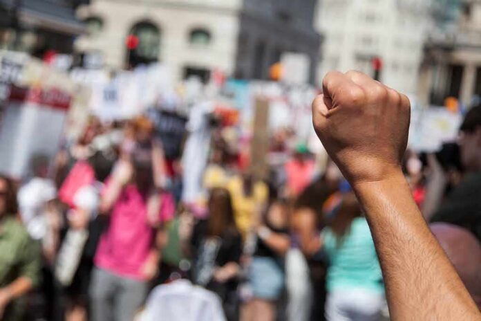 Raised fist in foreground at a crowded street protest