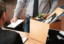 Employee holding resignation letter beside box of office belongings