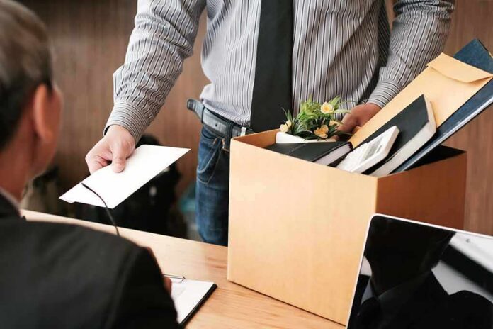 Employee holding resignation letter beside box of office belongings