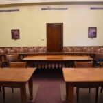 Romania Lowers the Boom on Tate Empty courtroom with wooden tables and gallery seating