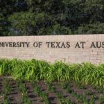 Sign for The University of Texas at Austin surrounded by greenery
