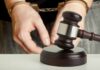 Handcuffed person behind judge's gavel