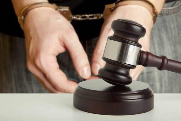 Handcuffed person behind judge's gavel
