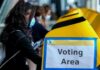 voter wearing a mask using a yellow ballot box