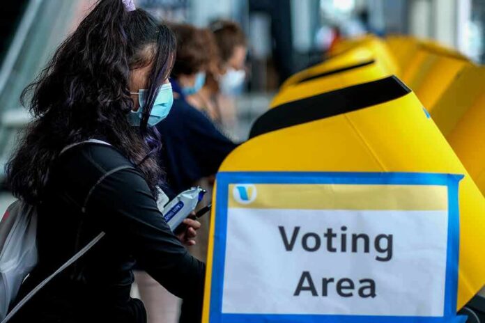 voter wearing a mask using a yellow ballot box