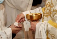 Priest gives communion wafer to a congregant