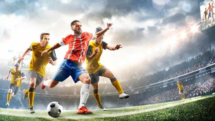 shutterstock_1992389864 Soccer player in red jersey sprints past defenders in a stadium