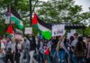 Wang Ying among protesters holding Palestinian flags and signs at a street demonstration