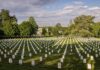Rows of white headstones in a cemetery under a partly cloudy sky