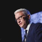 Man in suit and glasses speaking at podium