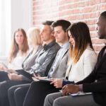 Job applicants seated in a row with clipboards