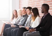 Job applicants seated in a row with clipboards