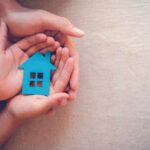 Hands holding a blue house cutout