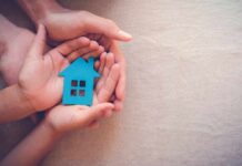 Hands holding a blue house cutout