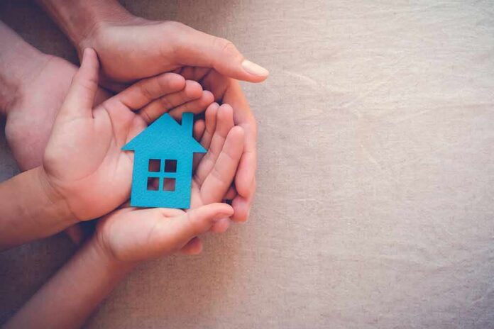 Hands holding a blue house cutout