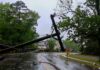 Fallen utility poles blocking a wet suburban street