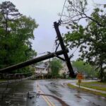 Fallen utility poles blocking a wet suburban street