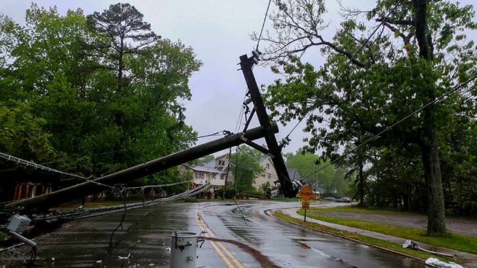 Fallen utility poles blocking a wet suburban street