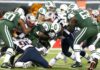 Football players collide in a heavy tackle at the line of scrimmage
