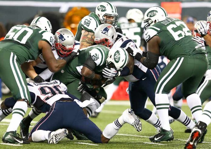 Football players collide in a heavy tackle at the line of scrimmage
