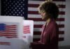 Voter at a polling booth with an American flag backdrop