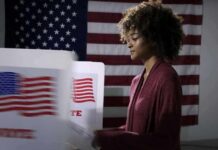 Ramaswamy Faces Backlash Over Acton’s Family Attack Ad Voter at a polling booth with an American flag backdrop