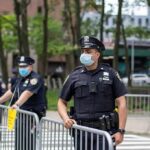 Walter Jones, a police officer in a face mask standing by metal barricades