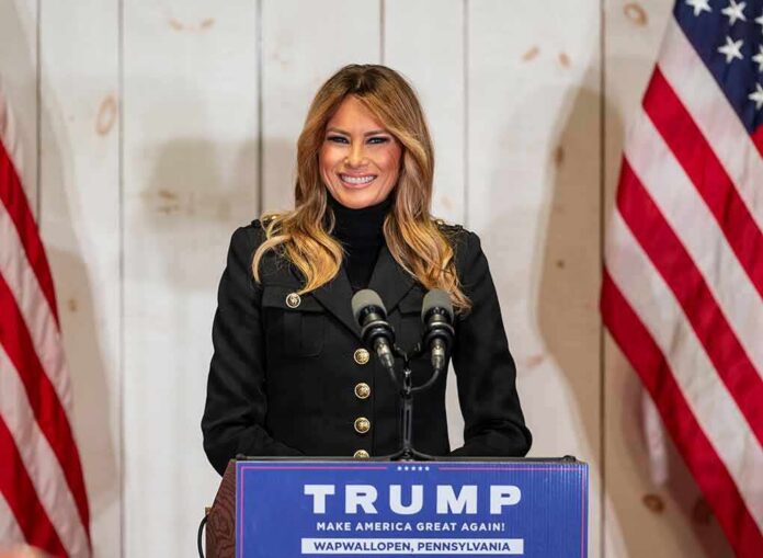 woman speaking at podium with microphones and US flags