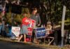 People at a campaign booth with political signs outdoors