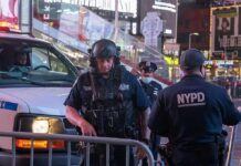 Police officers in tactical gear near a patrol vehicle at night