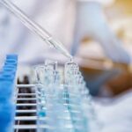 Pipette dispensing liquid into test tubes in a laboratory rack