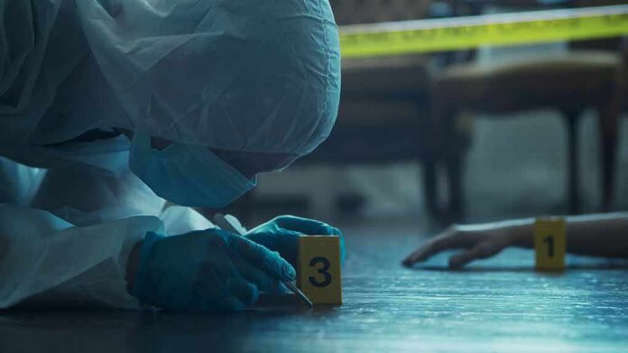 forensic investigator in protective suit examining crime scene markers