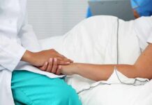 Healthcare worker holding a patient's hand in a hospital bed
