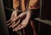 Prisoner in handcuffs behind jail bars