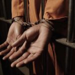 Prisoner in handcuffs behind jail bars