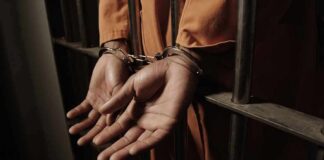 Prisoner in handcuffs behind jail bars