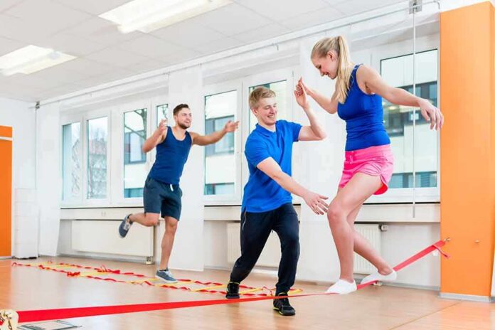 Three adults practicing slacklining indoors